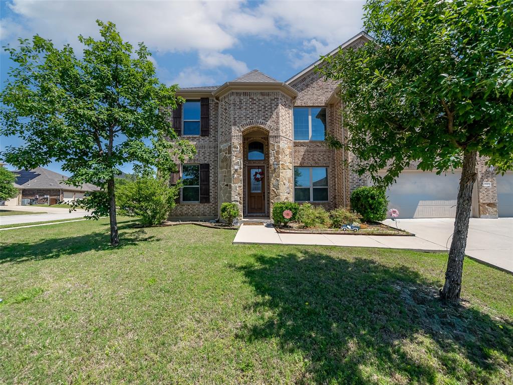 View of front of property with concrete driveway, brick siding, a front yard, and a garage