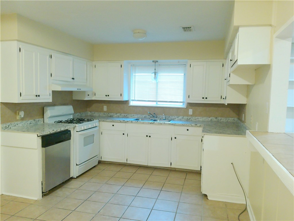 109 Sutherland Drive Portland, TX 78374 - Photo 2 of 17 a kitchen with granite countertop white cabinets and stainless steel appliances