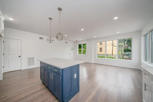 a kitchen with kitchen island a sink wooden floor and a large window