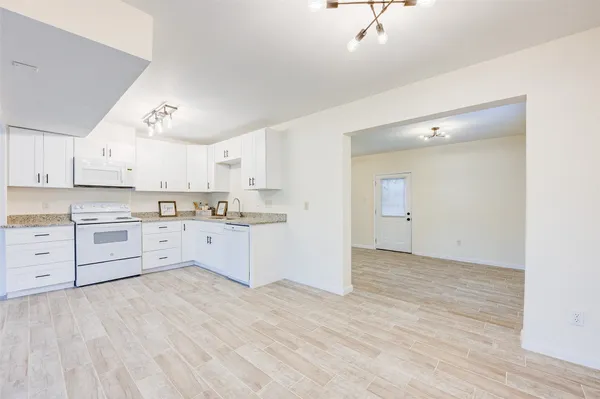 a large white kitchen with kitchen island a sink stainless steel appliances and cabinets