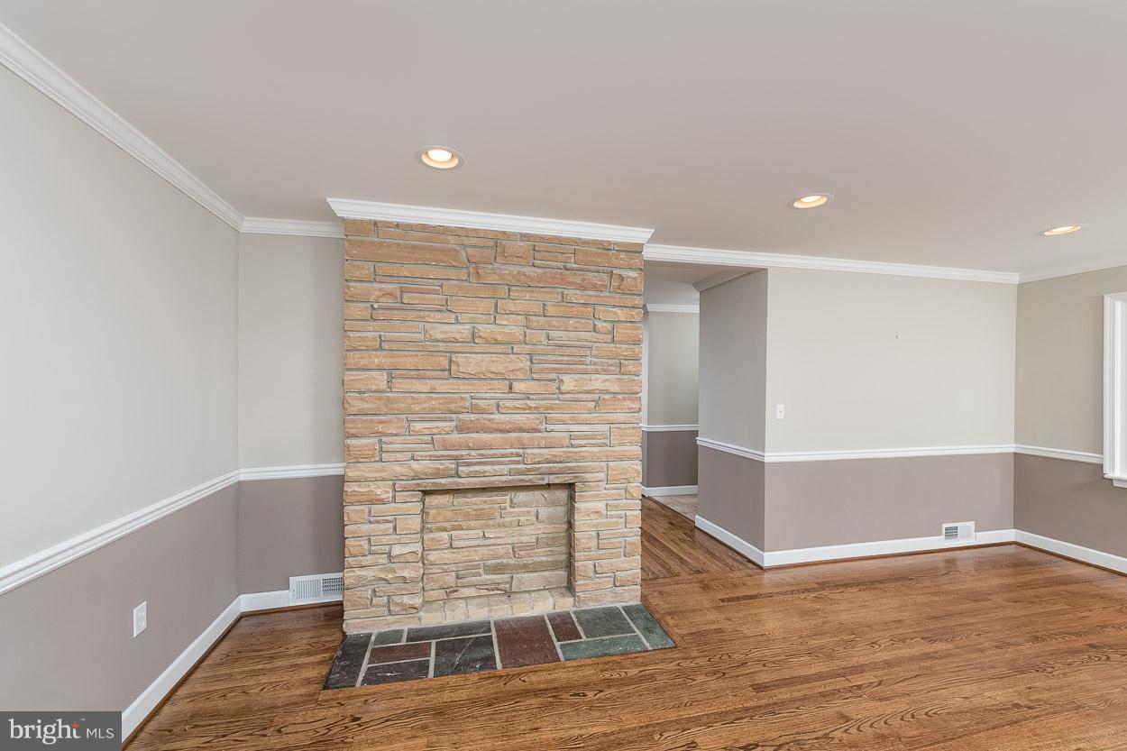 6629 Queens Ferry Road Baltimore, MD 21239 - Photo 14 of 28 a view of an empty room with wooden floor and a fireplace