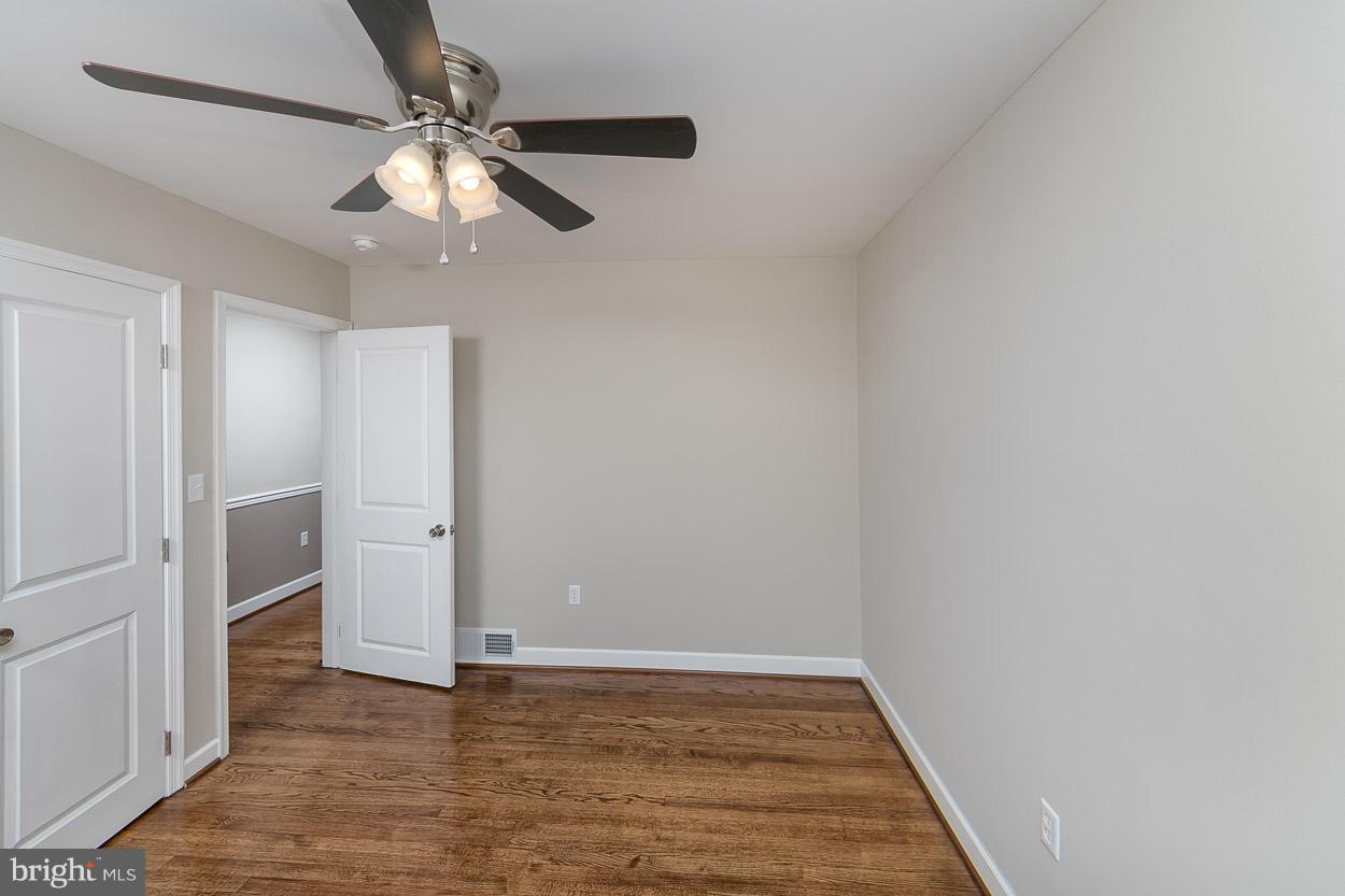 6629 Queens Ferry Road Baltimore, MD 21239 - Photo 22 of 28 an empty room with wooden floor closet and chandelier fan