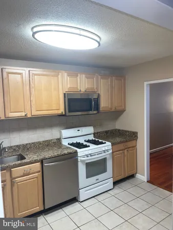 a kitchen with granite countertop white cabinets and white stainless steel appliances