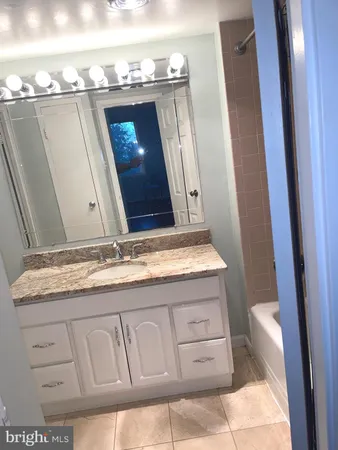 a bathroom with a granite countertop sink and a mirror