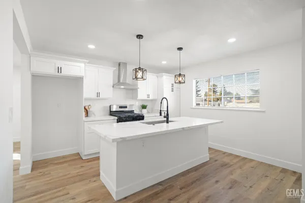 a kitchen with stainless steel appliances a sink a stove a refrigerator cabinets and wooden floor