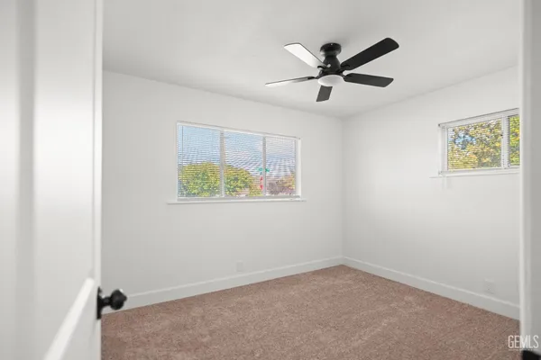 an empty room with ceiling fan and window