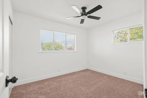 an empty room with a window and a ceiling fan