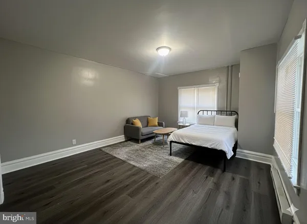 a spacious bedroom with a bed and wooden floor