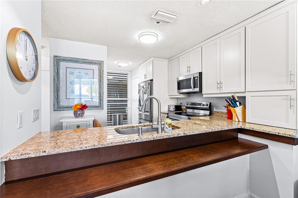 615 Dream Island Road, Unit 202 Longboat Key, FL 34228 - Photo 16 of 66 a kitchen with kitchen island granite countertop white cabinets and stainless steel appliances