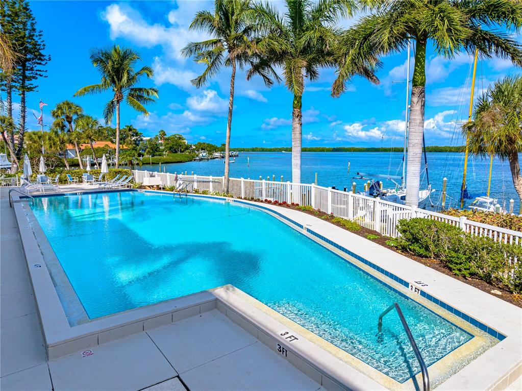 615 Dream Island Road, Unit 202 Longboat Key, FL 34228 - Photo 56 of 66 a view of swimming pool with a lawn chairs under an umbrella