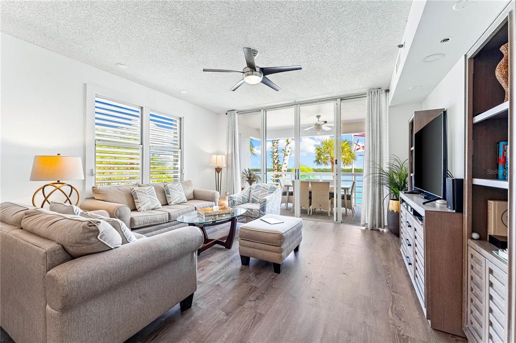 615 Dream Island Road, Unit 202 Longboat Key, FL 34228 - Photo 10 of 66 a living room with furniture a ceiling fan and a flat screen tv