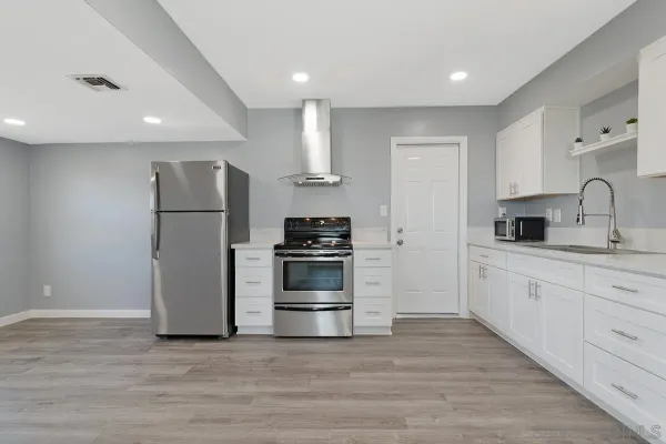 a kitchen with granite countertop a refrigerator stove and white cabinets