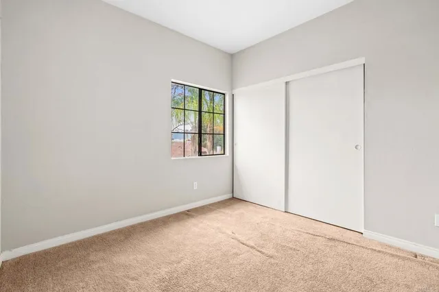 an empty room with a chandelier fan and windows