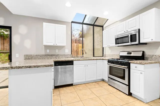 a kitchen with stainless steel appliances granite countertop a stove a sink and a microwave