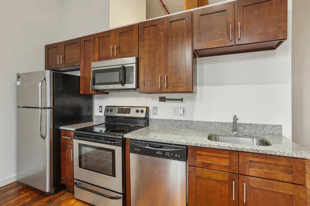 a kitchen with granite countertop a sink stove and refrigerator