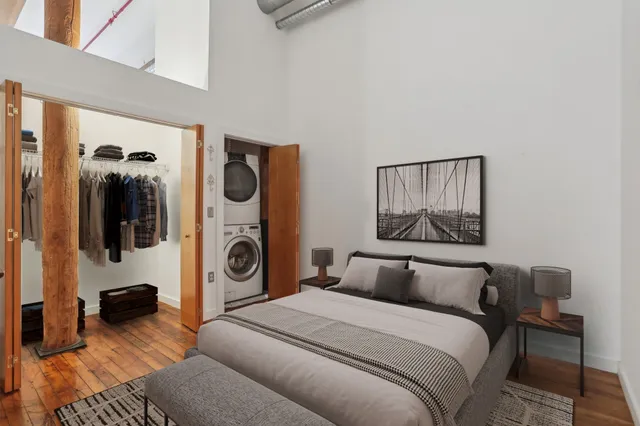 a bedroom with a bed and walk in closet with wooden floor