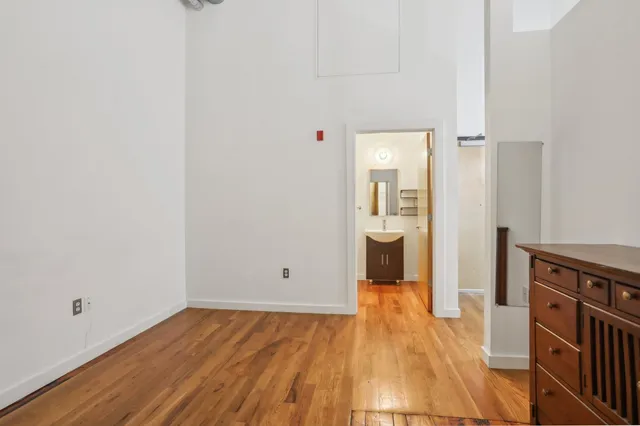 a view of a hallway with wooden floor and a bathroom