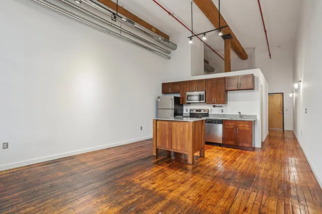 a kitchen with stainless steel appliances wooden floor and a sink