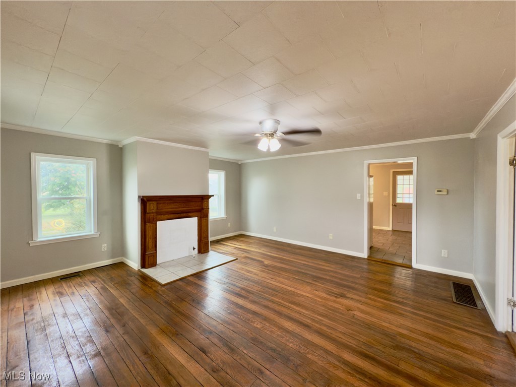 2109 Bell Road Vincent, OH 45784 - Photo 30 of 49 Unfurnished living room featuring crown molding, dark wood-type flooring, a ceiling fan, and a tiled fireplace