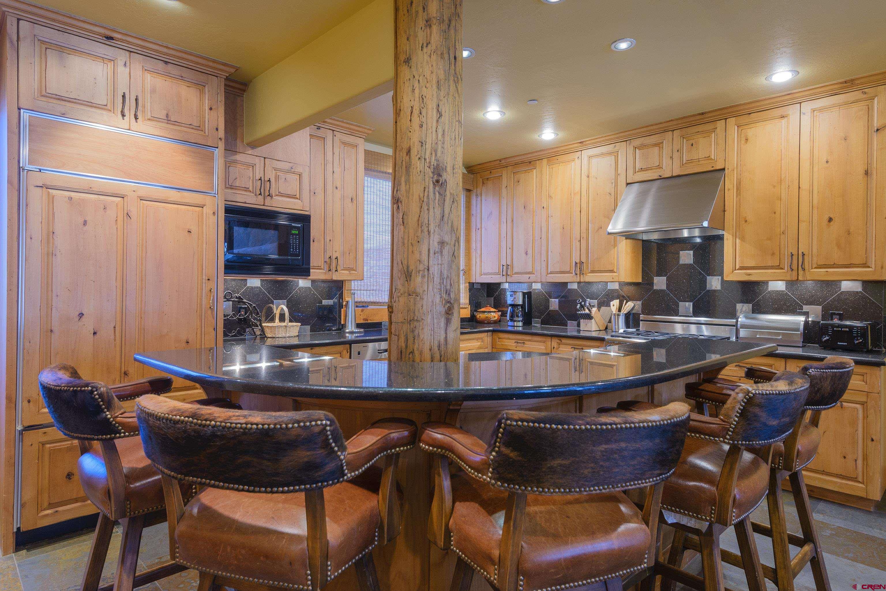 16 Snowmass Road, Unit 7 Crested Butte, CO 81225 - Photo 22 of 37 a kitchen with granite countertop a table chairs stove a sink and dishwasher