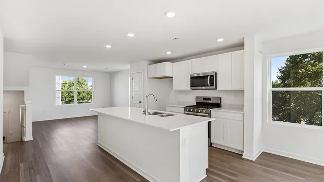 a kitchen with a sink stainless steel appliances and wooden floor
