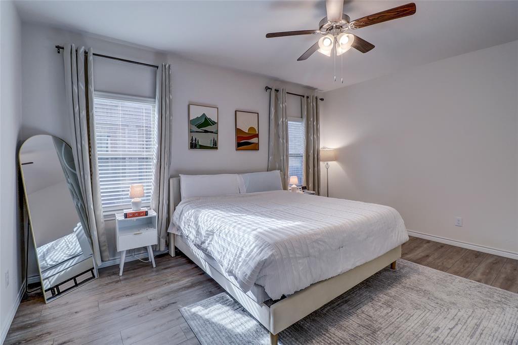 7404 Seton Place McKinney, TX 75071 - Photo 13 of 29 a bedroom with a bed wooden floor and a flat tv screen