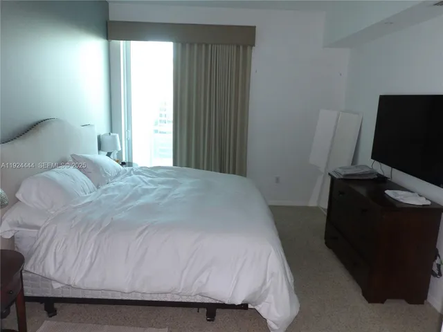 a bedroom with a bed tv and a window