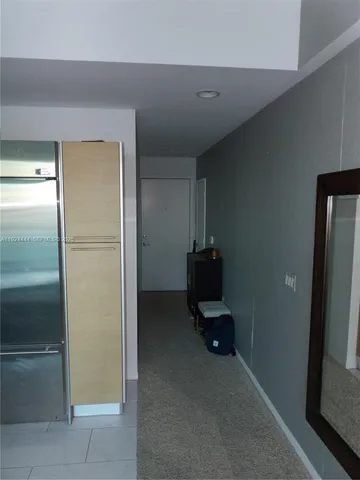 a view of a refrigerator in kitchen and an empty room