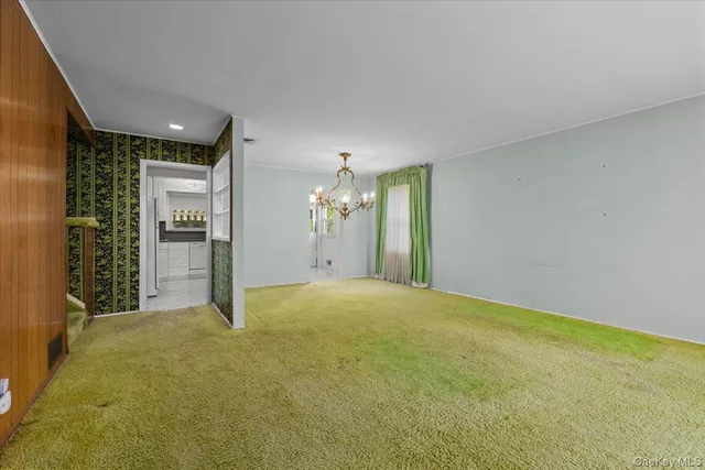 a view of an empty room with chandelier and bathroom