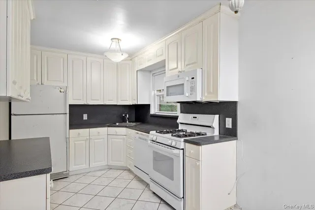 a kitchen with white cabinets and appliances