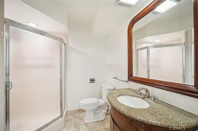 a bathroom with a granite countertop sink a mirror and a toilet
