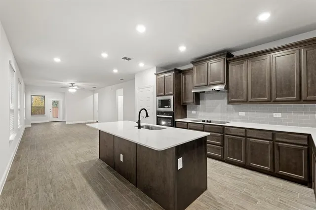 a large kitchen with stainless steel appliances granite countertop a sink counter space and cabinets