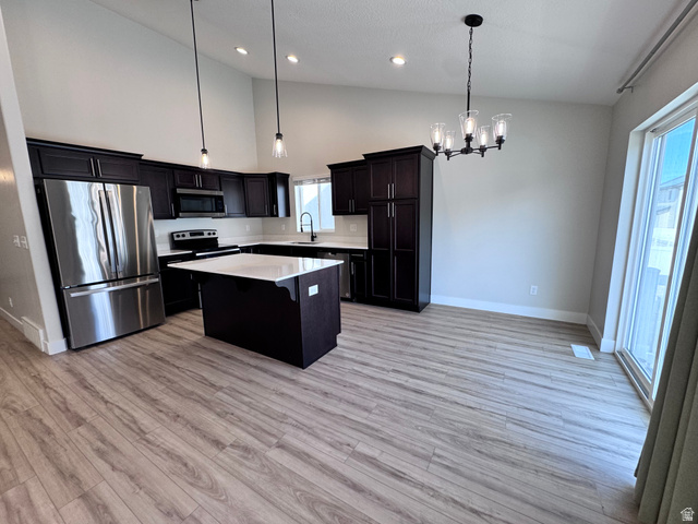 12339 Remy Road, Unit 422 Herriman, UT 84096 - Photo 12 of 36 Kitchen featuring stainless steel appliances, suspended lighting, a center island, lofted ceiling, and light wood-style floors