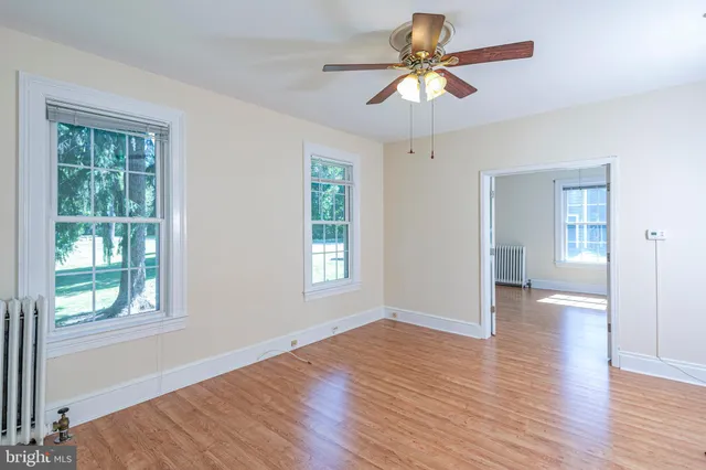 a view of an empty room with window and wooden floor