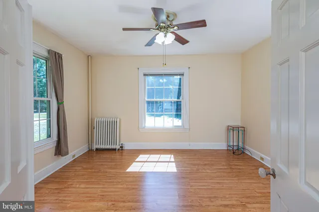 a view of an empty room with a window and wooden floor