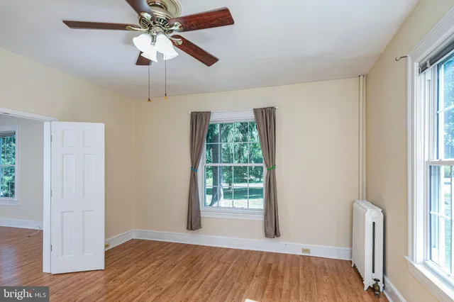 a view of an empty room with a window and wooden floor