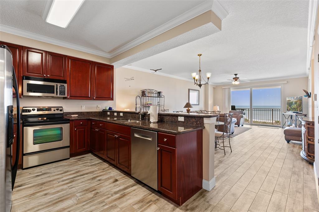 60 Surfview Drive, Unit 502 Palm Coast, FL 32137 - Photo 2 of 63 a kitchen with stainless steel appliances granite countertop a stove top oven a sink dishwasher and wooden cabinets with wooden floor