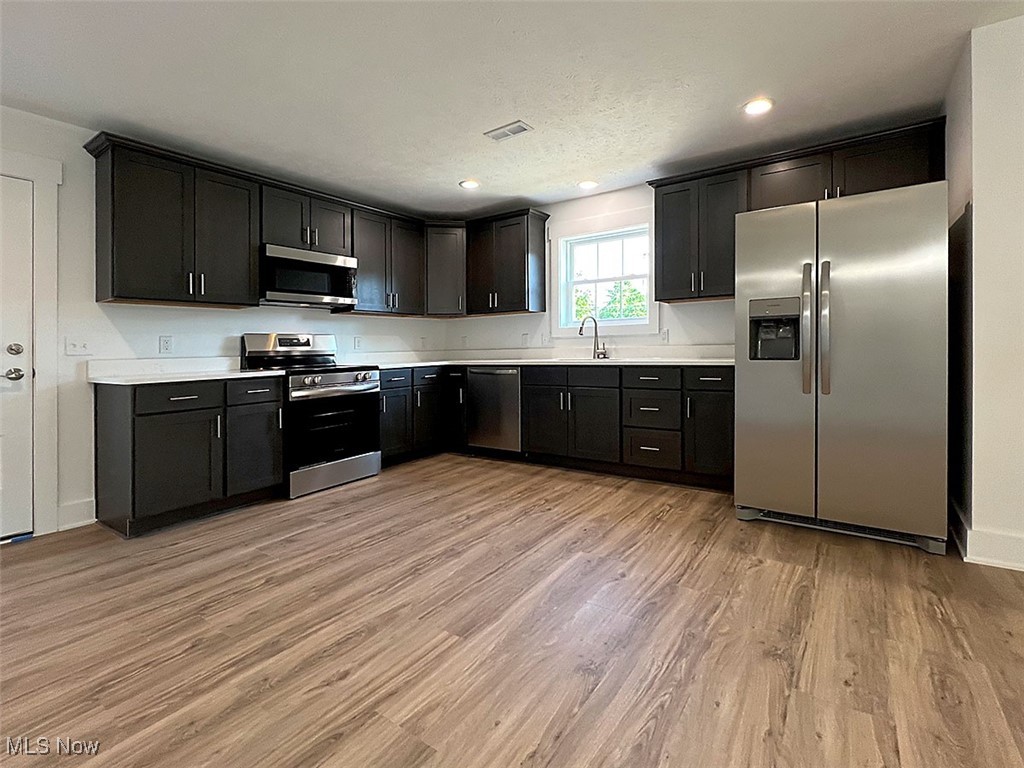 3641 Menlo Road Cleveland, OH 44120 - Photo 7 of 26 Open concept kitchen featuring appliances with stainless steel finishes, quartz countertops, light wood-style flooring, shaker cabinets, and recessed lighting