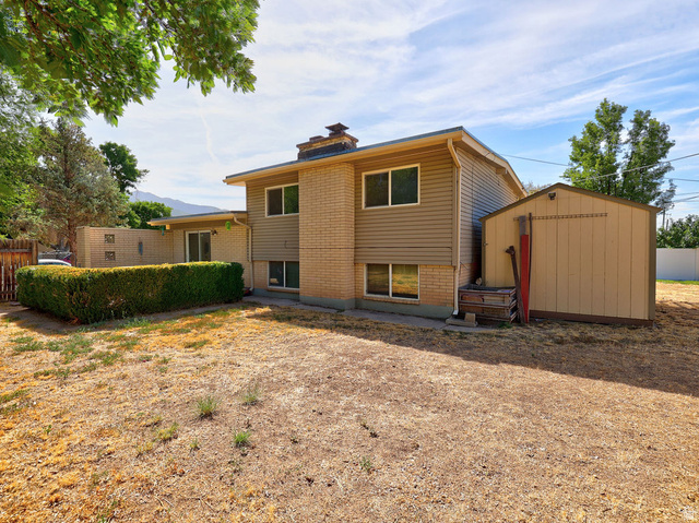 669 Colonial Avenue Layton, UT 84041 - Photo 45 of 51 Rear exterior with a storage shed, a manicured hedge, and a sliding glass door