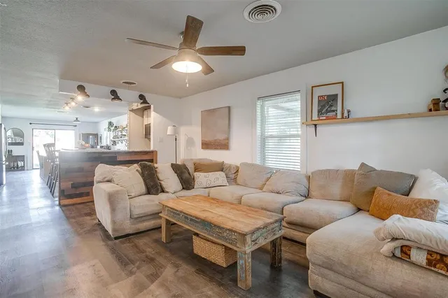 a kitchen with stainless steel appliances kitchen island granite countertop a stove a sink a microwave a dining table and chairs with wooden floor