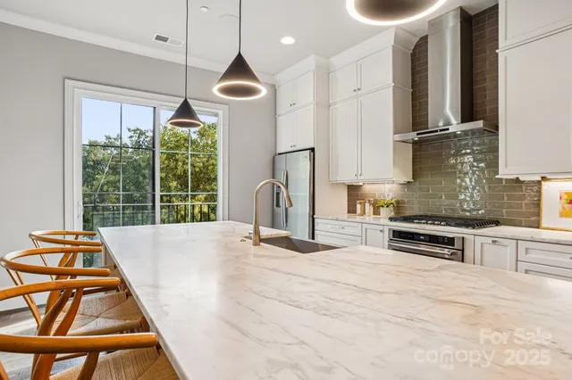 a large white kitchen with stainless steel appliances granite countertop a stove and a wooden floors