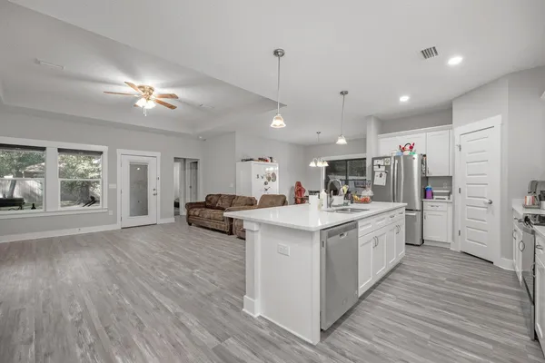 a large kitchen with kitchen island a stove a refrigerator a sink dishwasher with a dining table and chairs with wooden floor