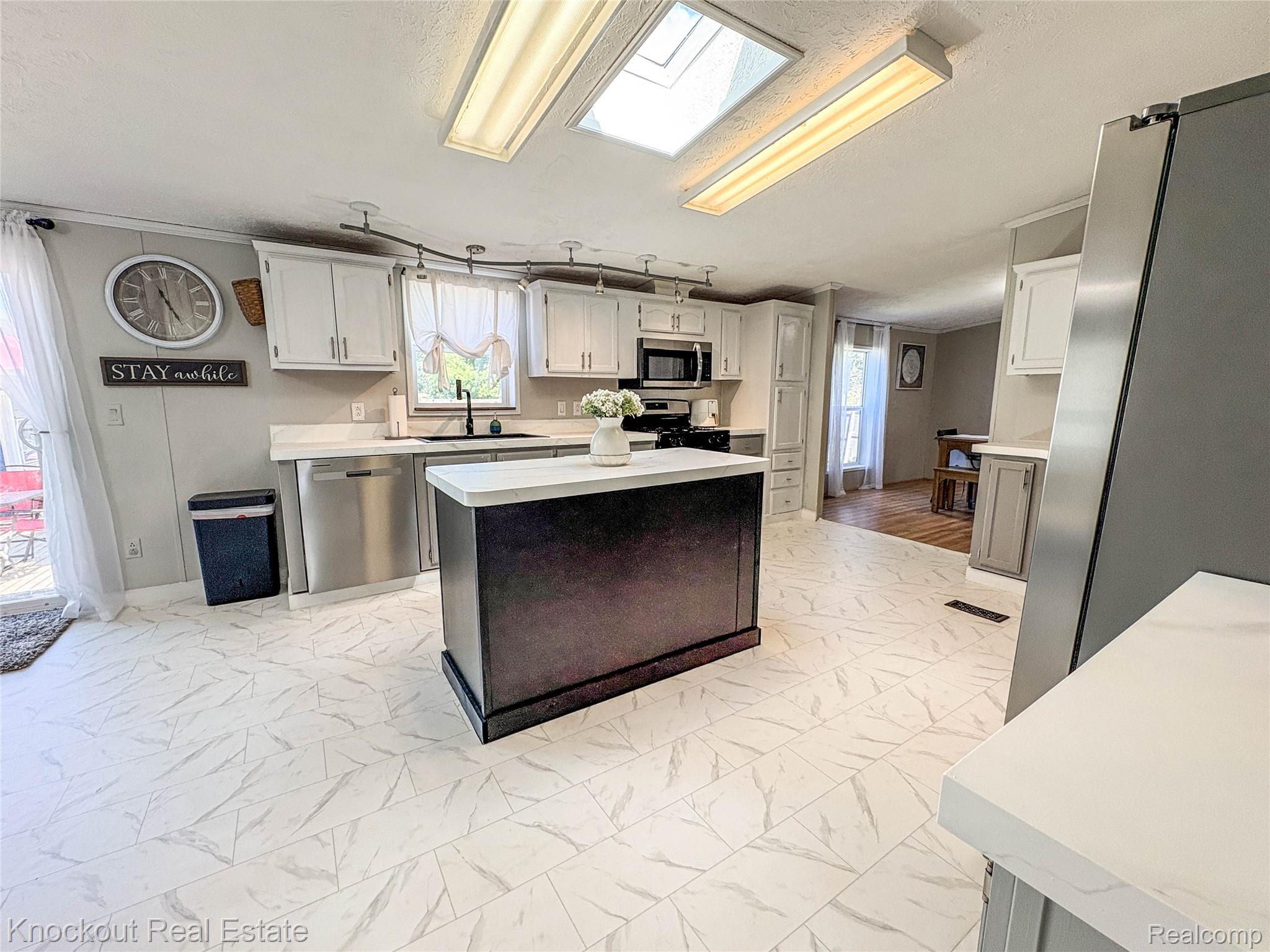 7760 Bell Road Birch Run, MI 48415 - Photo 14 of 68 Kitchen featuring a central island with countertop, white cabinetry, stainless steel appliances, and tile flooring