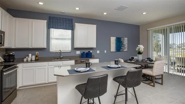 a kitchen with a dining table chairs sink and white cabinets