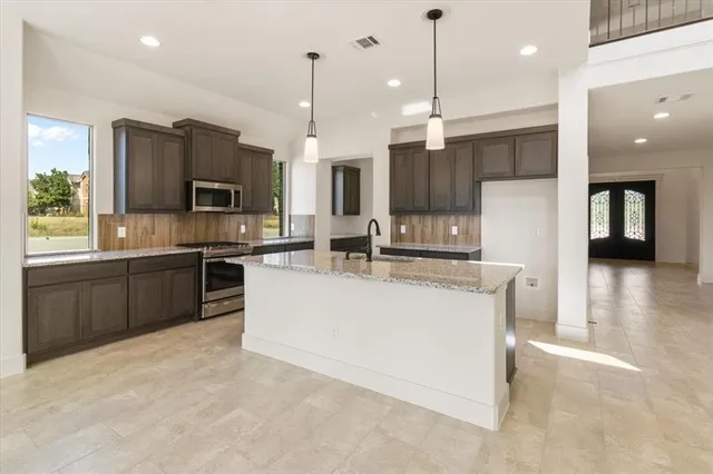 a kitchen with kitchen island a sink stainless steel appliances and cabinets