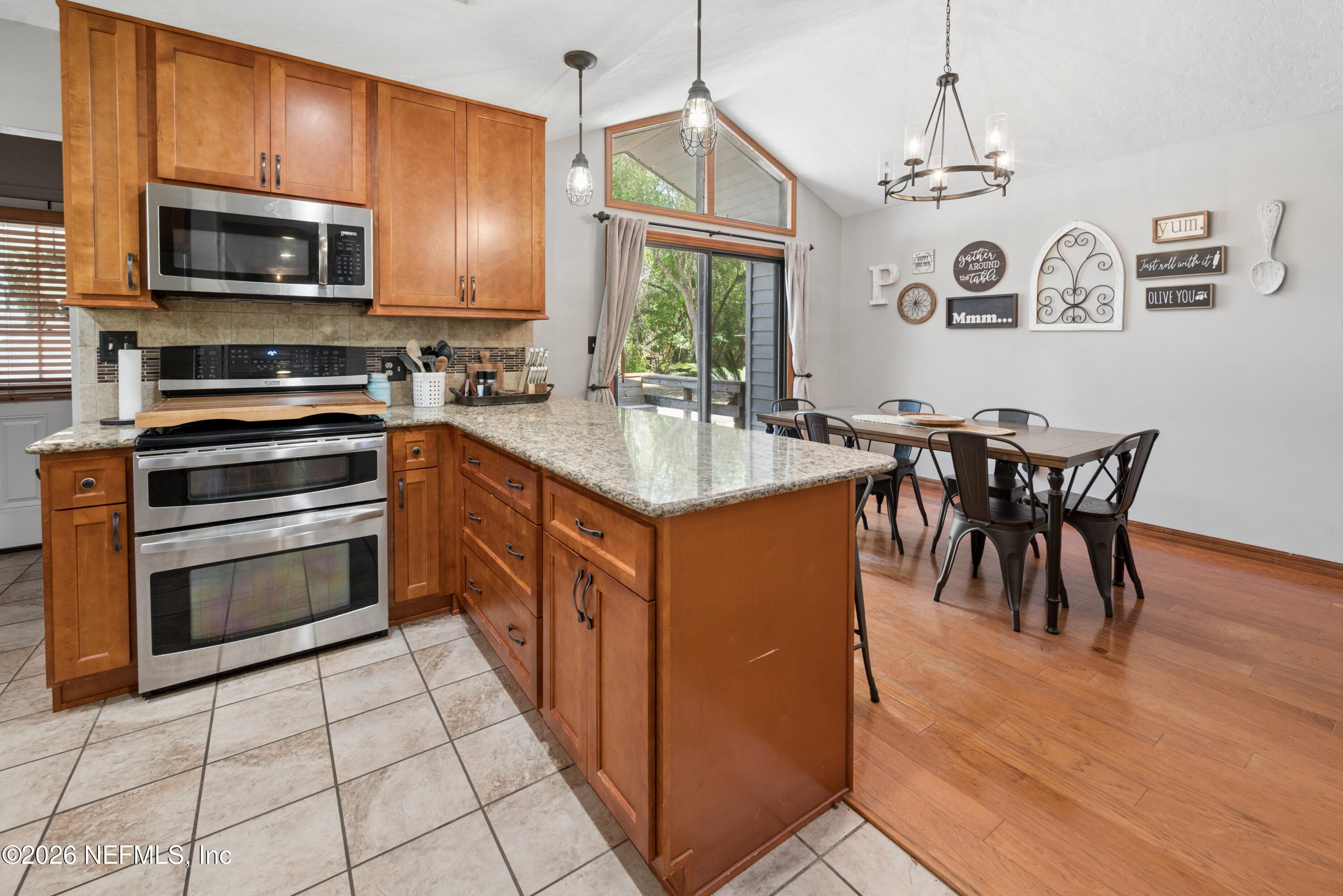 6519 Neale Road Melrose, FL 32666 - Photo 16 of 48 a kitchen with stainless steel appliances granite countertop a stove top oven a sink dishwasher a dining table and chairs with wooden floor
