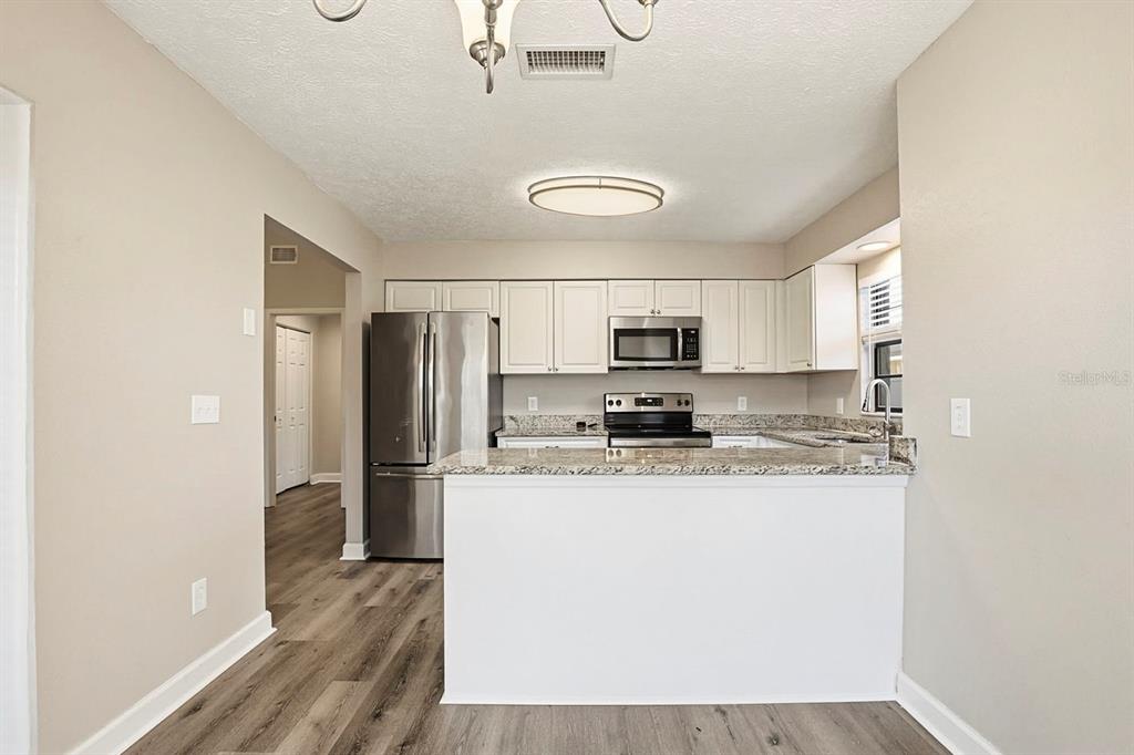 15009 Naples Place Tampa, FL 33624 - Photo 18 of 42 a kitchen with stainless steel appliances granite countertop a refrigerator a stove a sink and white cabinets with wooden floor
