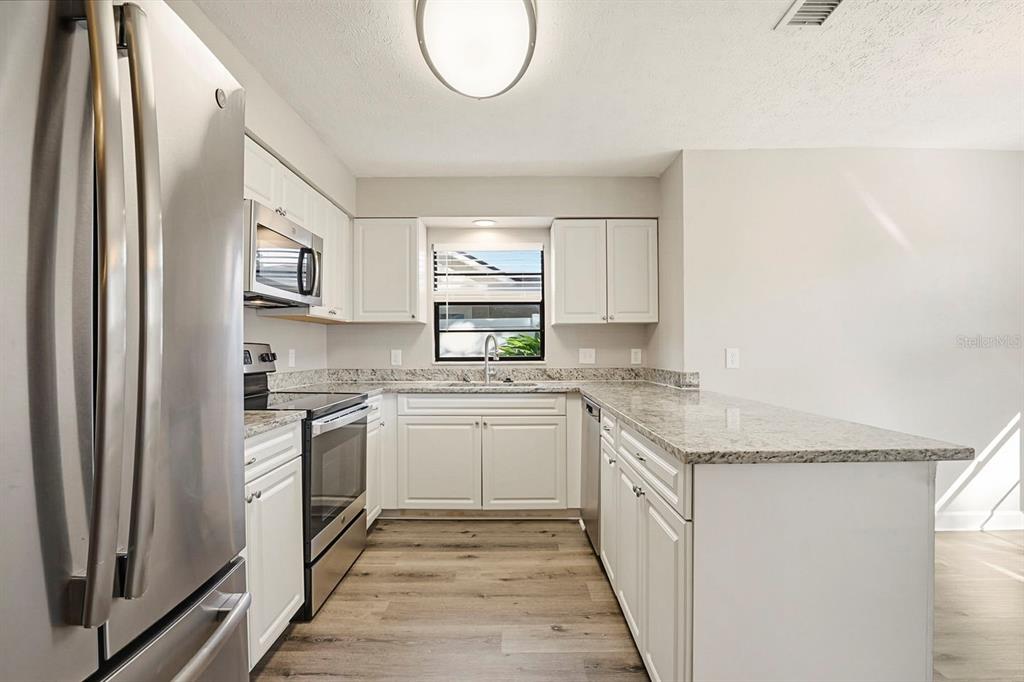 15009 Naples Place Tampa, FL 33624 - Photo 19 of 42 a kitchen with stainless steel appliances granite countertop a stove a sink and a refrigerator