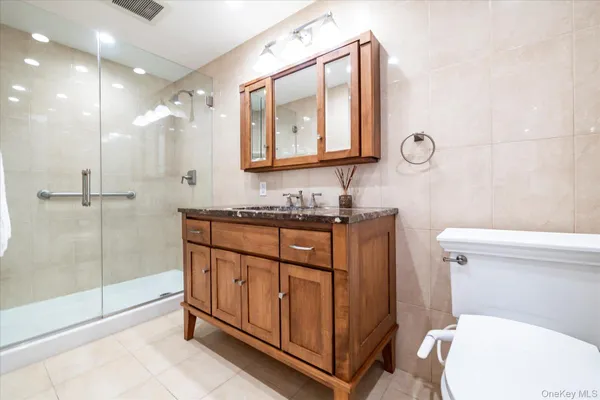 a bathroom with a granite countertop sink mirror vanity and toilet