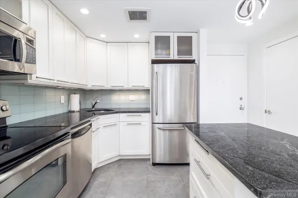 a kitchen with granite countertop a sink stove and refrigerator